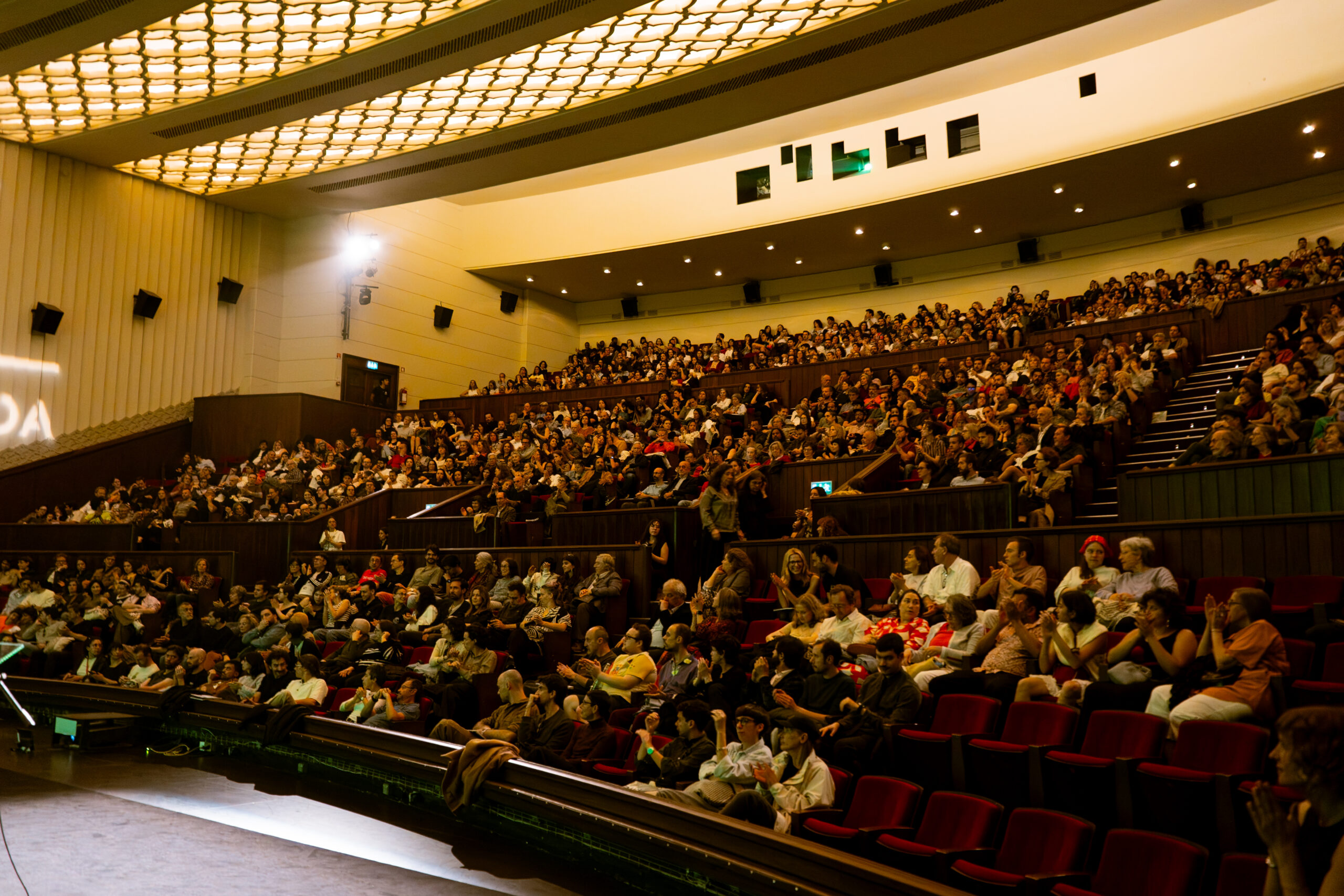 A photograph of the main auditorium at Cinema São Jorge, with many seats occupied by the audience.